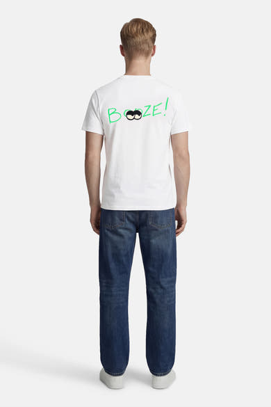 Wit T-shirt met korte mouwen van ANTWRP, met humoristische opdruk op de rug, gedragen met een blauwe jeans en witte schoenen.