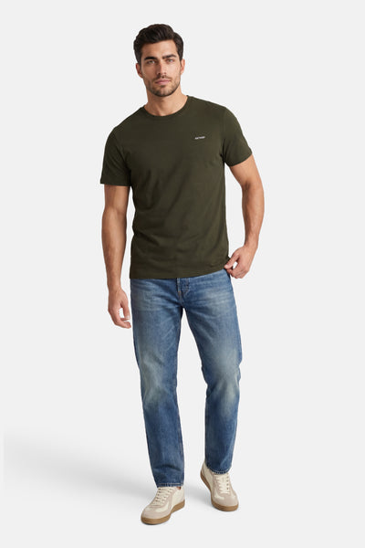 T-shirt kaki à manches courtes d'ANTWRP, porté avec un jean bleu et des baskets beige.