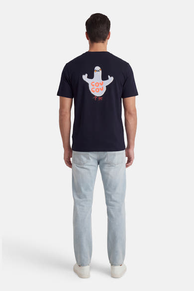 T-shirt à manches courtes bleu de ANTWRP, avec un imprimé de pigeon et porté avec un jean clair et des chaussures blanches.