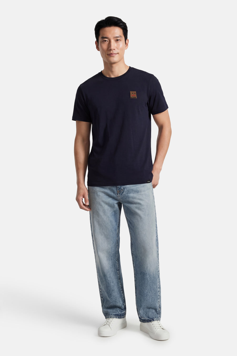 T-shirt à manches courtes bleu d'ANTWRP, avec un patch logo sur la poitrine, porté avec un jean délavé et des baskets blanches.
