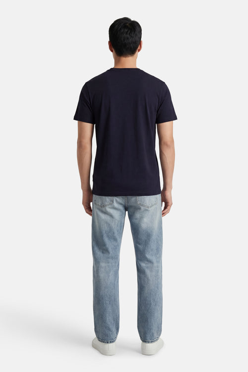 T-shirt à manches courtes bleu de ANTWRP, porté avec un jean délavé et des chaussures de sport blanches, vue de dos.
