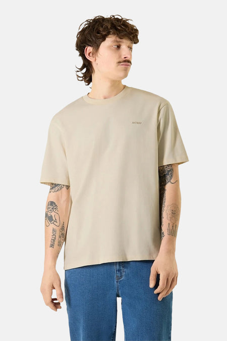 Ecru T-shirt met korte mouwen van ANTWRP, gedragen met een blauwe jeans, met tatoeages op de armen.