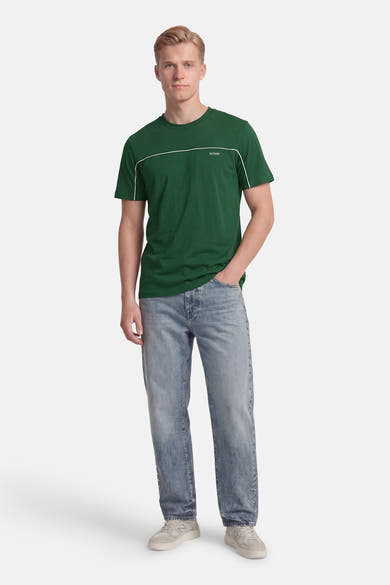 T-shirt à manches courtes vert de ANTWRP, avec liserés blancs aux manches et col, porté avec un jean et des baskets.
