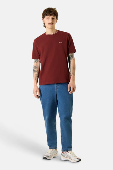 T-shirt bordeaux à manches courtes d'ANTWRP, porté avec un jean bleu et des baskets blanches.