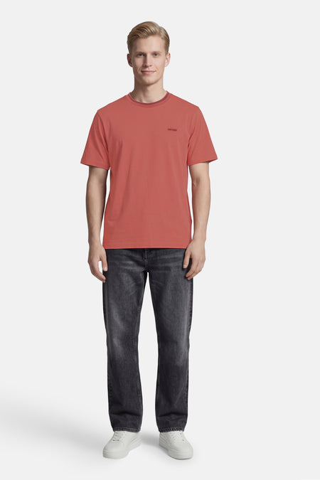 Roze T-shirt met korte mouwen van ANTWRP met opdruk op de borst, gedragen met een grijze jeans en witte sneakers.