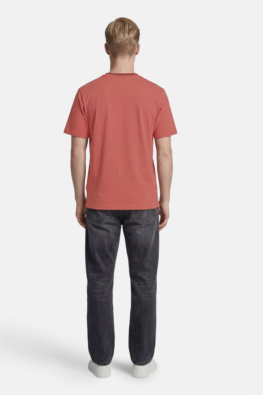 T-shirt rose de ANTWRP, avec col rond côtelé, porté de dos avec un jean gris foncé et des baskets blanches.