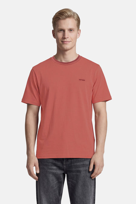 Roze T-shirt met korte mouwen van ANTWRP met een ronde hals met strepen en een opdruk op de borst, gedragen met een donkere spijkerbroek.