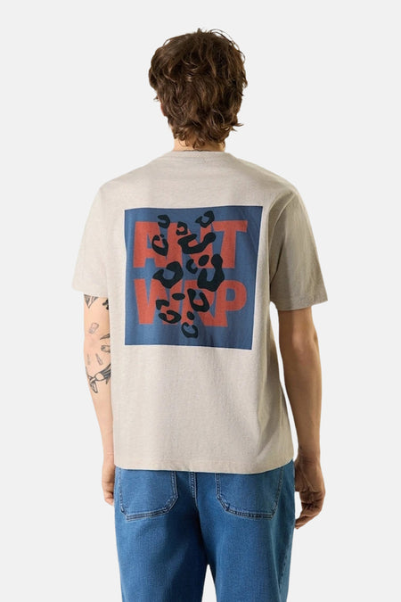 Beige T-shirt ANTWRP met rood en blauw luipaardpatroon op de rug, gedragen met een blauwe jeans en witte sneakers.
