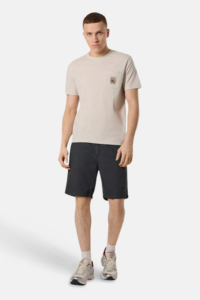 T-shirt beige à poche de ANTWRP, porté avec un short noir et des baskets.