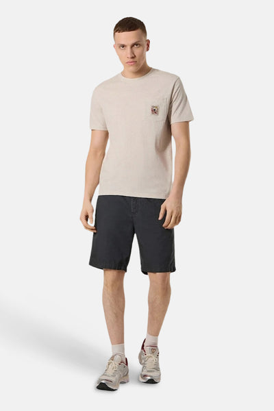 T-shirt beige à poche de ANTWRP, porté avec un short noir et des baskets.