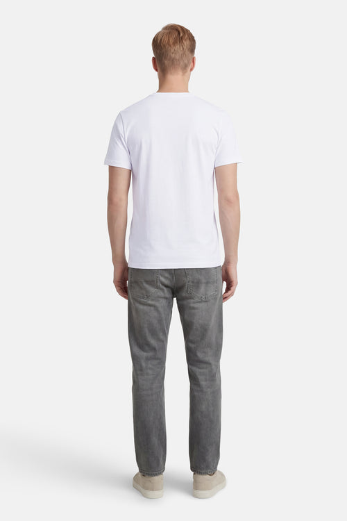 T-shirt à manches courtes blanc de ANTWRP, vue de dos, porté avec un jean gris et des chaussures couleur crème.
