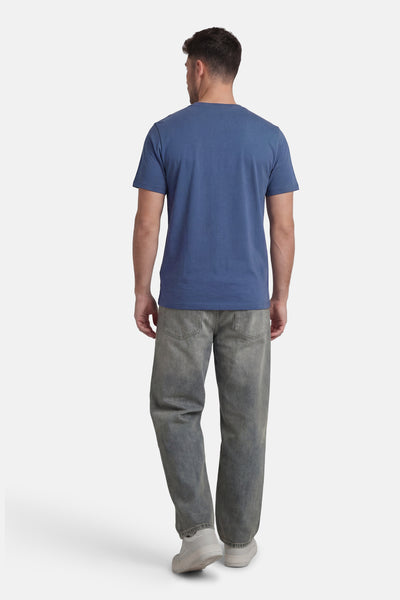 T-shirt à manches courtes bleu de ANTWRP, porté avec un pantalon décontracté gris et des chaussures de sport blanches, vue de dos.
