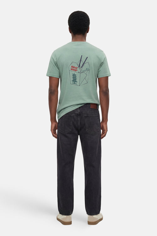 T-shirt à manches courtes vert de ANTWRP, avec motif d'un récipient de nouilles, porté avec un jean noir.
