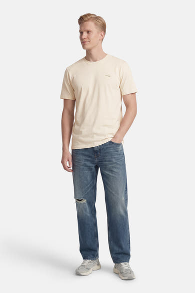 T-shirt à manches courtes écru de ANTWRP, porté avec un jean bleu délavé et des baskets grises.