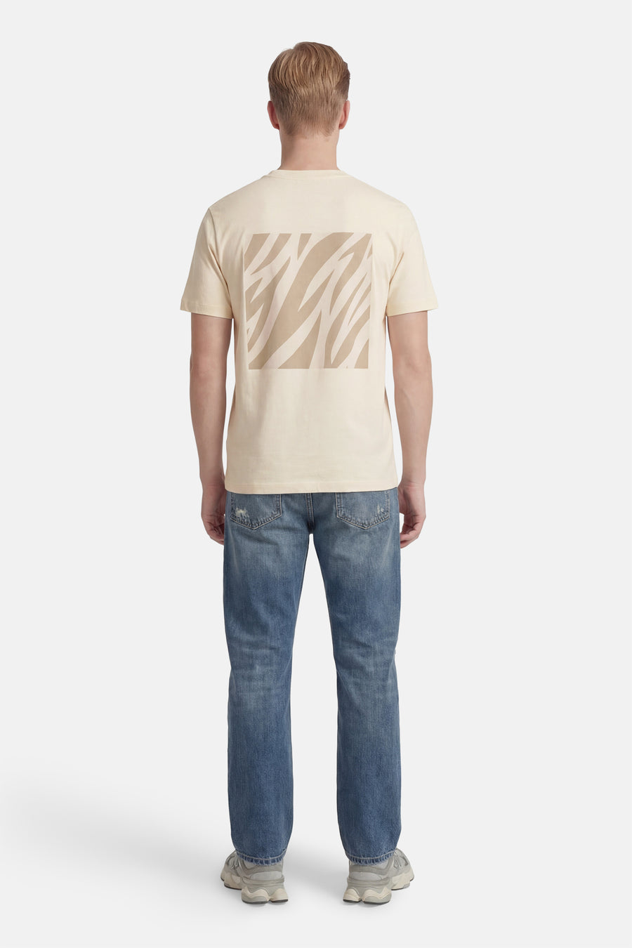 T-shirt à manches courtes écru de ANTWRP, avec motif imprimé zébré sur le dos, porté avec un jean bleu.
