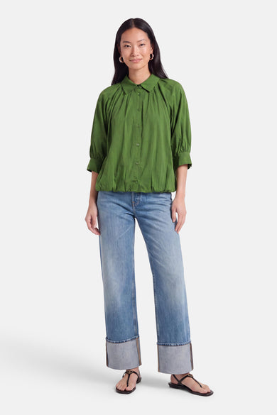 Chemise à manches courtes olive de AMELIE ET AMELIE, col boutonné, plissé au devant, vue frontale sur modèle portant jeans et sandales.