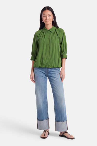 Chemise à manches courtes olive de AMELIE ET AMELIE, col boutonné, plissé au devant, vue frontale sur modèle portant jeans et sandales.
