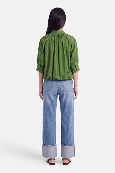 Chemise verte à manches courtes par AMELIE ET AMELIE, vue dos, avec plissé au col et poignets boutonnés, portée avec jeans larges et sandales.