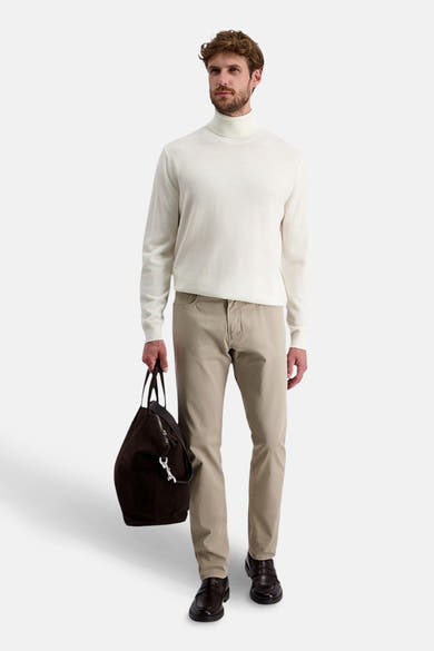 Pantalon coloré beige de PIERRE CARDIN porté avec un pull à col roulé et des mocassins en cuir.