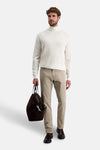 Pantalon coloré beige de PIERRE CARDIN porté avec un pull à col roulé et des mocassins en cuir.