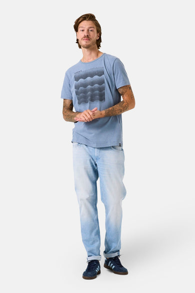 Blauwe korte mouw T-shirt van GARCIA met een grafisch patroon, gedragen met een lichte jeans en blauwe marineschoenen.