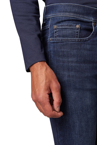 Jean droit bleu par PIERRE CARDIN avec poche gousset et détail de surpiqûres, porté avec un t-shirt bleu marine.