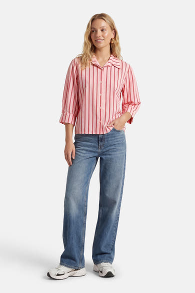 Chemisier rose à manches courtes par AMELIE ET AMELIE, à rayures verticales rouges, porté avec un jean bleu.
