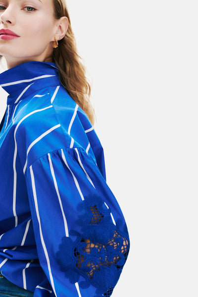 Blauwe gestreepte blouse van CAROLL met pofmouwen en bloemenkanten details, zijwaarts bekeken.