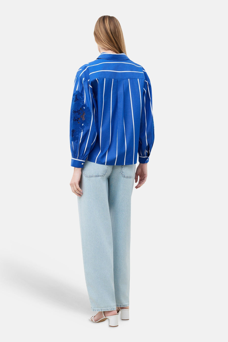 Chemise bleue à rayures verticales blanches de CAROLL, avec détails en dentelle sur la manche.