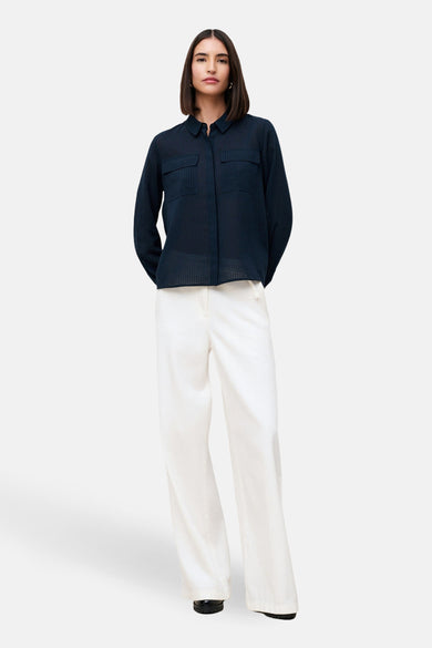 Chemise à manches longues bleu par CAROLL, avec texture quadrillée, portée avec un pantalon blanc.