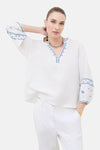 Witte blouse van lichte stof van CAROLL met 3/4 mouwen en blauwe borduursels op de mouwen, achterzijde.