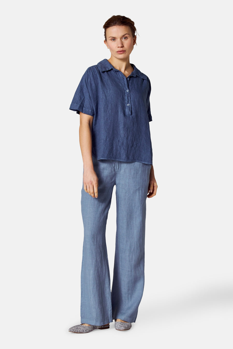 Blauwe blouse met korte mouwen van COPINES D'ANVERS, met knoopsluiting en gedragen met een bijpassende blauwe broek.
