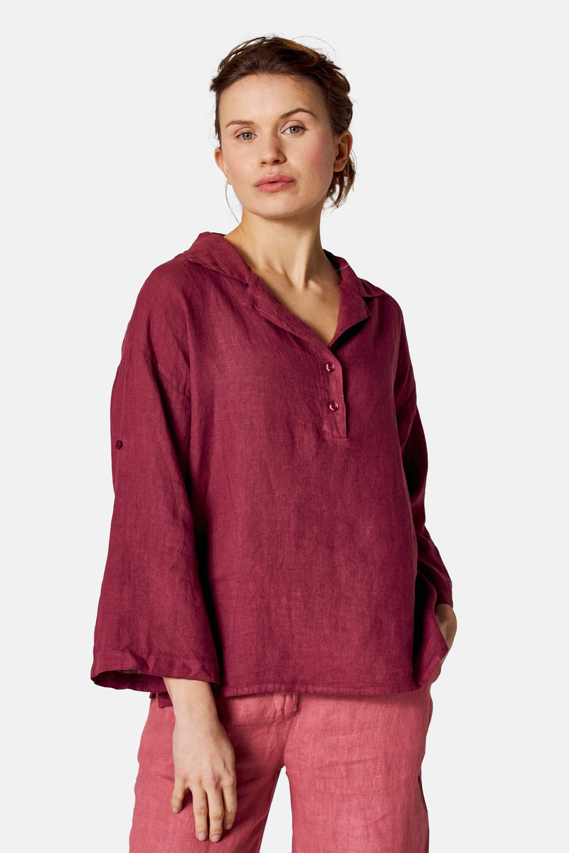 Chemisier bordeaux à manches courtes de COPINES D'ANVERS avec deux boutons, porté avec un pantalon rose.