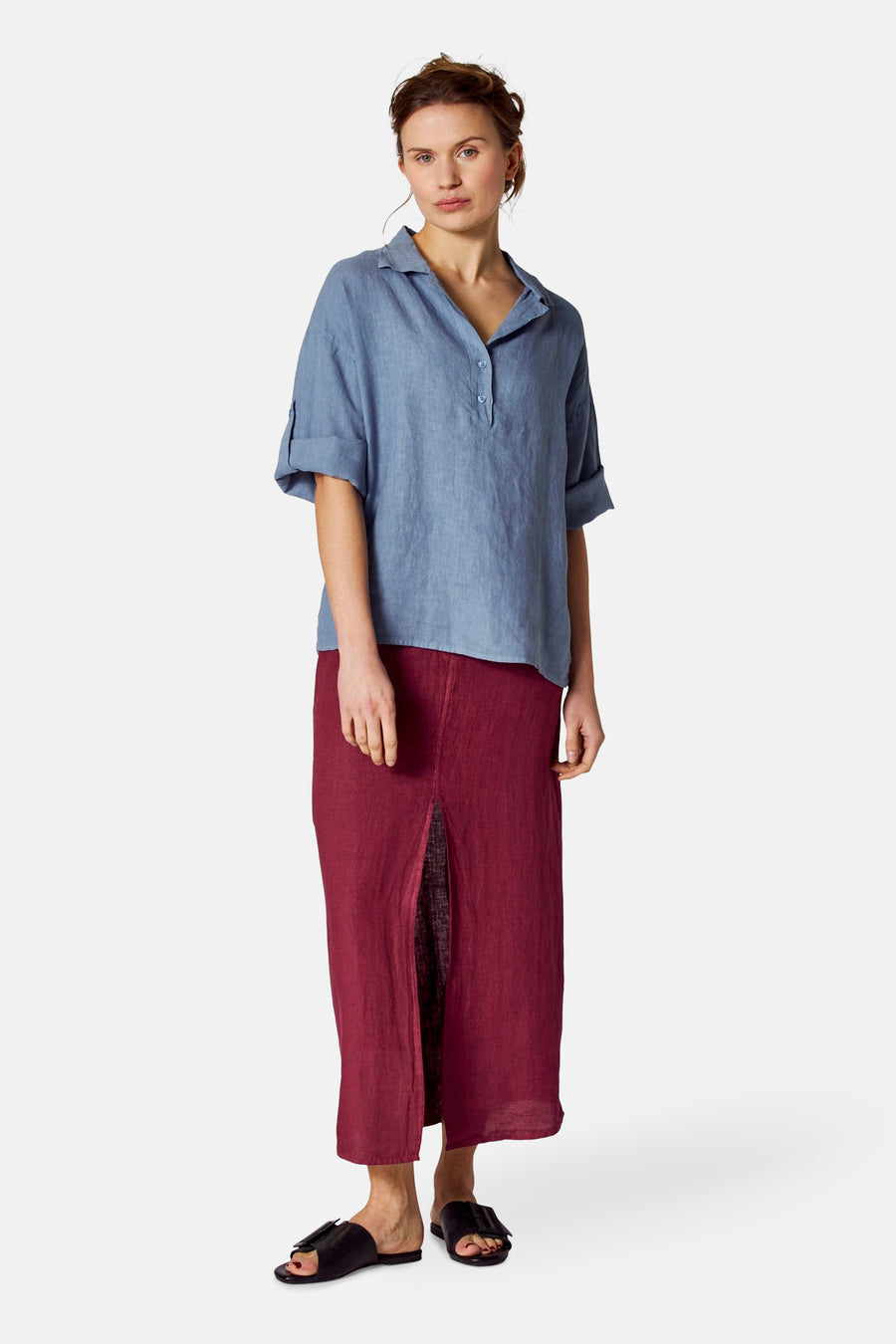 Blauwe blouse met korte mouwen van COPINES D'ANVERS gedragen met een lange bordeauxrode rok met split en zwarte sandalen.