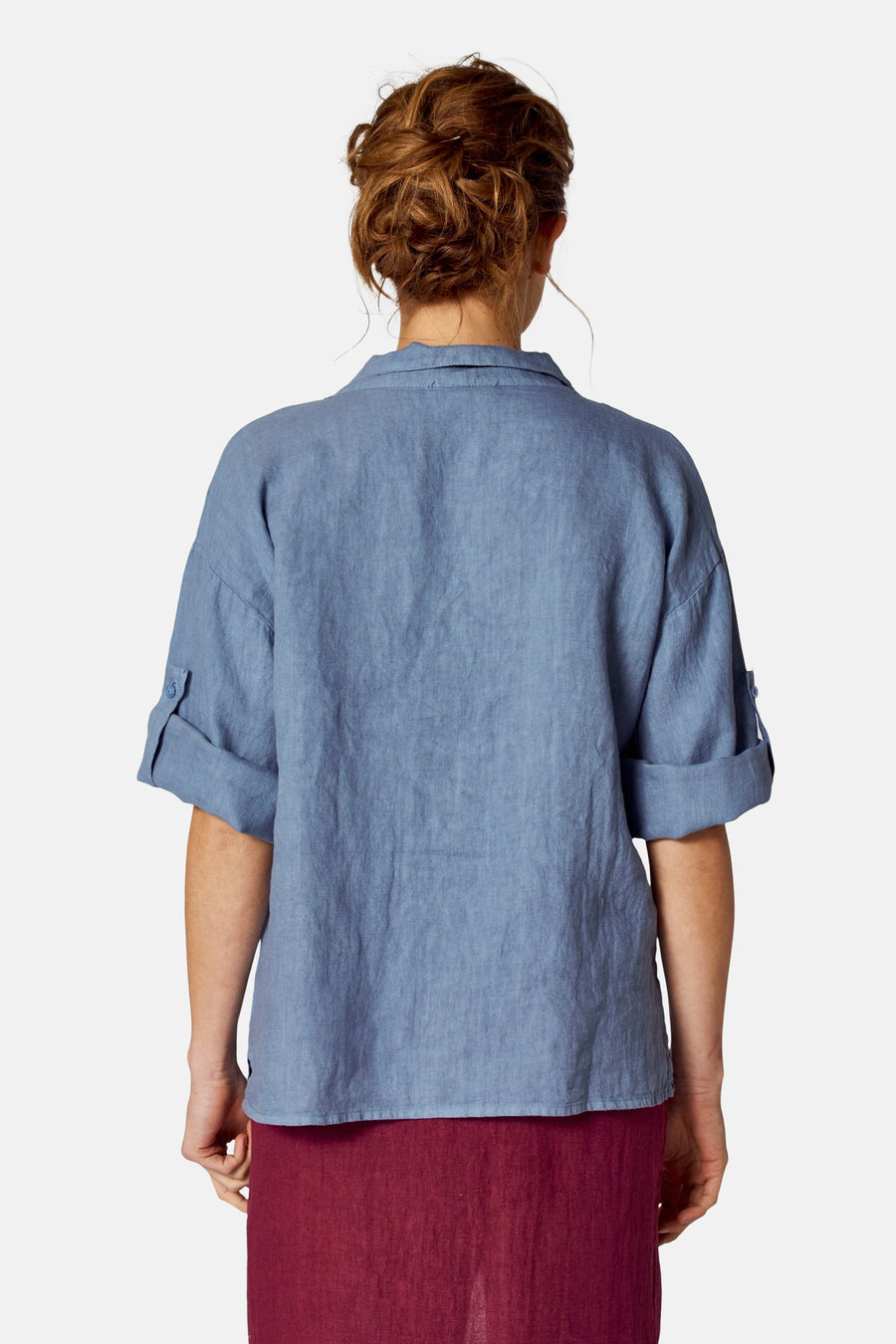 Blauwe blouse (korte mouwen) van COPINES D'ANVERS met opgerolde mouwen en linnen textuur, gedragen met een bordeauxrode rok.