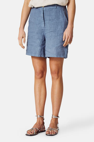 Blauwe linnen bermudashort van COPINES D'ANVERS, gedragen met zilveren sandalen, vooraanzicht.