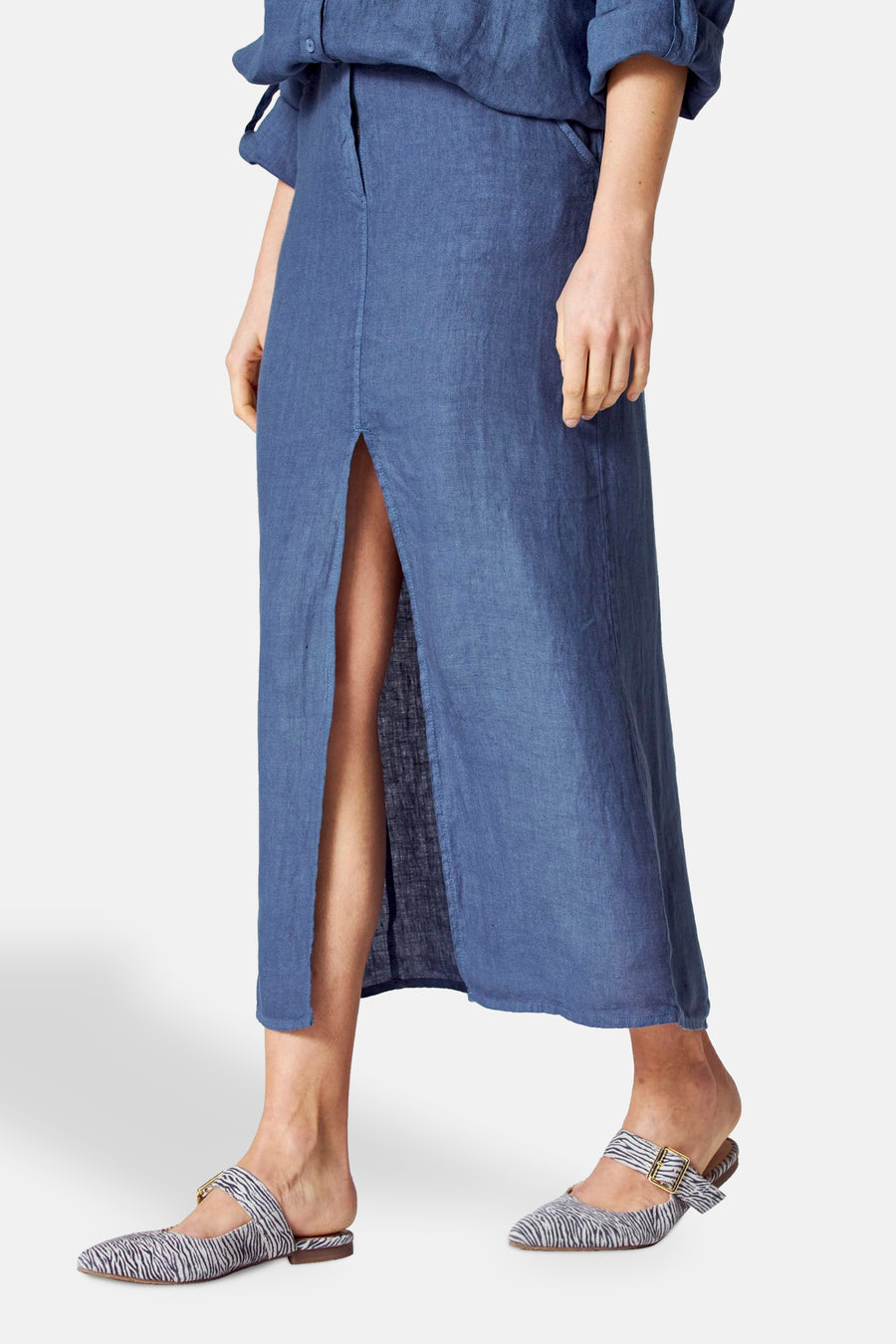 Lange blauwe linnen rok van COPINES D'ANVERS, met een centrale split en zichtbare gestreepte schoenen.