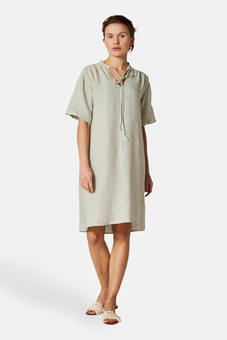 Groene jurk van COPINES D'ANVERS, met trekkoord, gedragen met sandalen met franjes.