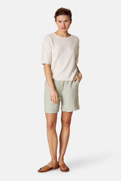Ronde mouw ecru van COPINES D'ANVERS, gedragen met een groene broek en bruine sandalen.