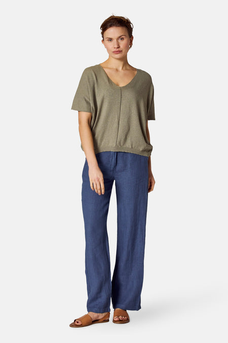 Groen gebreid topje van COPINES D'ANVERS, met een V-hals en korte mouwen, gedragen met een blauwe broek.