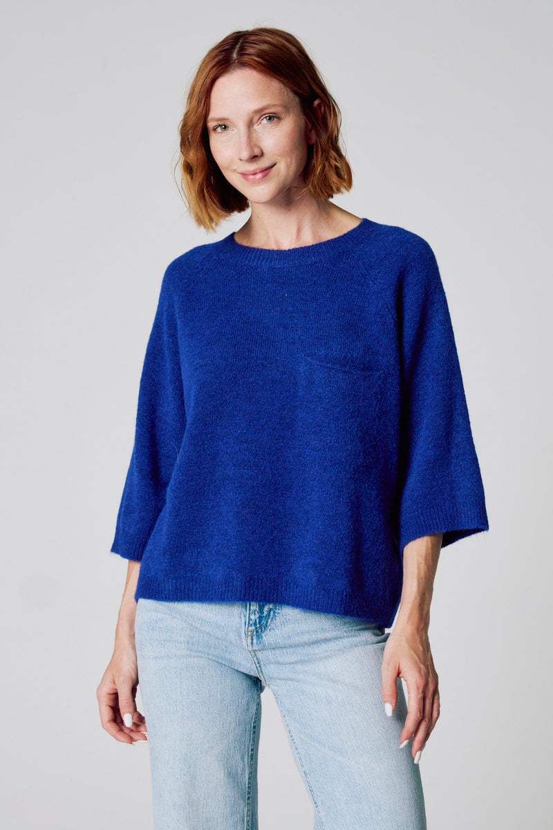 Pull bleu à col rond de COPINES D'ANVERS, porté avec un jean clair.