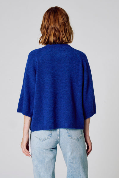 Pull à col rond bleu de COPINES D'ANVERS, porté avec un jean taille haute clair, vue de dos.
