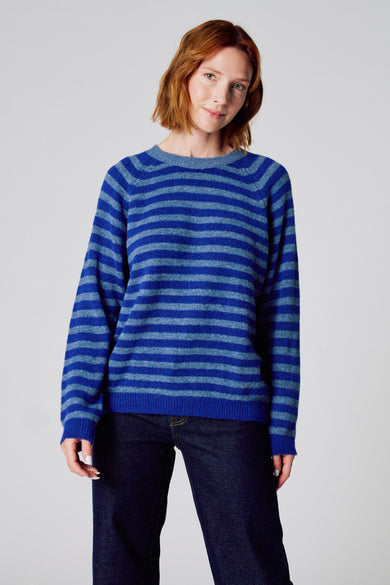 Pull à col rond bleu par COPINES D'ANVERS à rayures horizontales, porté avec un jean bleu.
