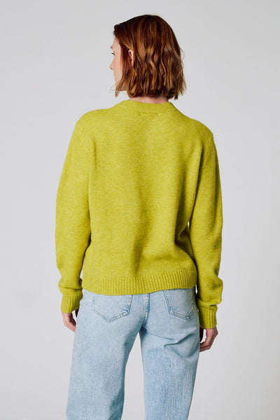 Groene, getextureerde gebreide cardigan van COPINES D'ANVERS, gedragen met een high-waisted jeans, achtergezicht.