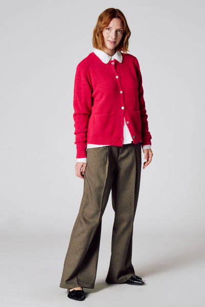 Roze vest van COPINES D'ANVERS, gedragen met een witte blouse met geschulpte kraag en een wijde bruine broek.