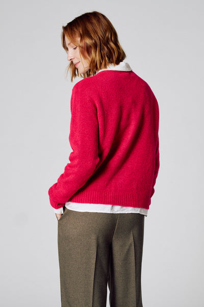 Roze coltrui van COPINES D'ANVERS, gedragen over een wit overhemd, met een wollen broek met visgraatmotief.
