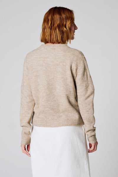 Taupe vest van COPINES D'ANVERS, lange mouwen, gedragen met een witte rok, achterzicht.