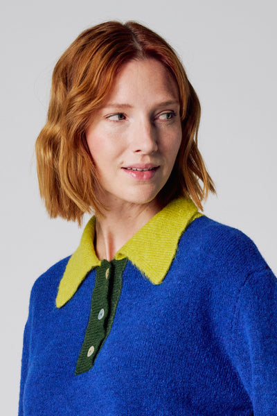 Blauwe trui met ronde hals van COPINES D'ANVERS, met olijfgroene knoopsluiting en parelmoeren knopen.