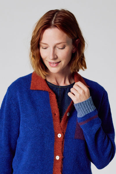 Cardigan bleu en maille par COPINES D'ANVERS, avec col et patte de boutonnage contrastants.