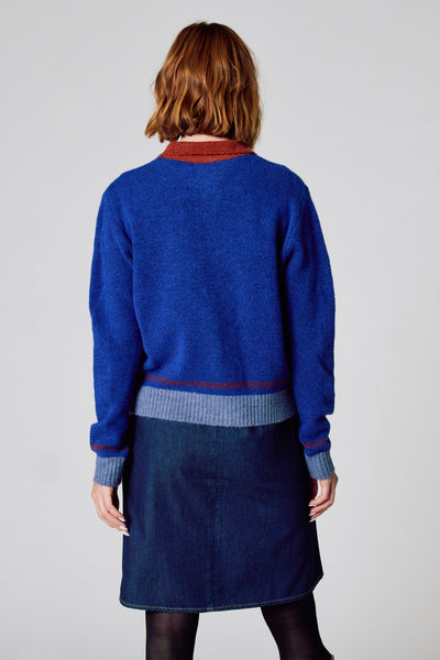 Ronde hals trui van COPINES D'ANVERS in het blauw, met contrasterende afwerkingen aan de hals en taille, gedragen met een spijkerrok.